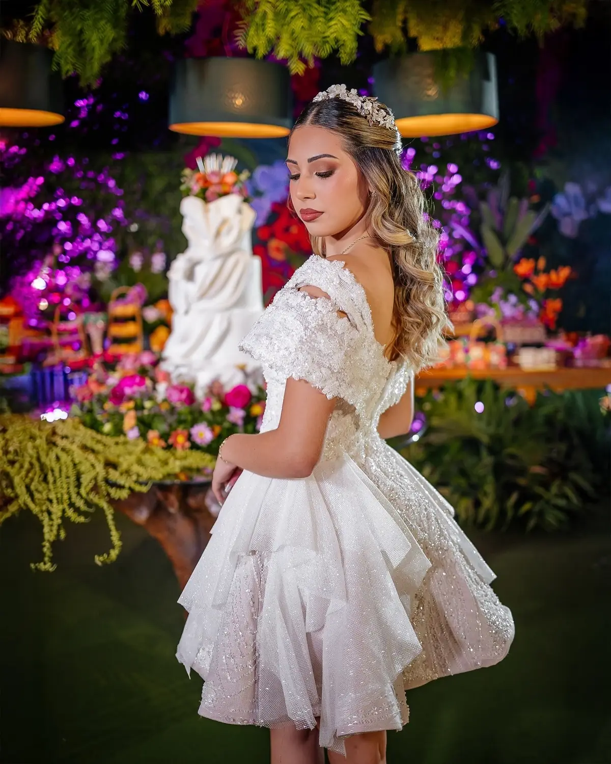 Quinceañera con vestido blanco corto en un salón decorado con flores