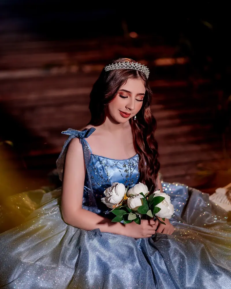 Quinceañera con vestido azul en un jardín de noche