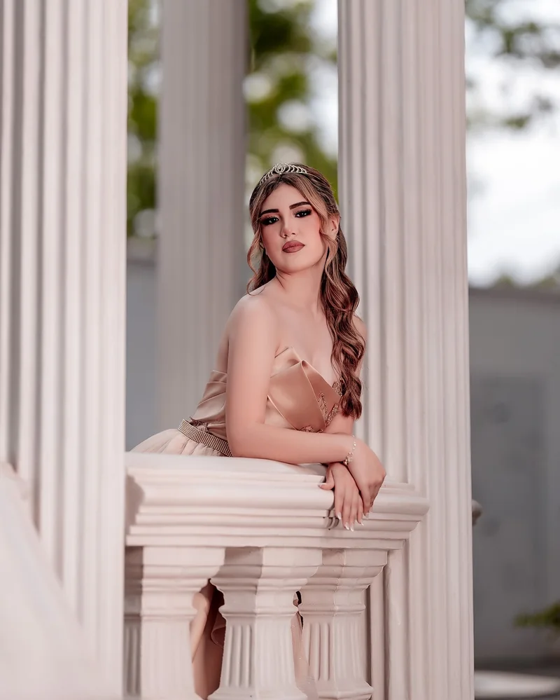 Quinceañera sentada en una escalera blanca con su vestido extendido